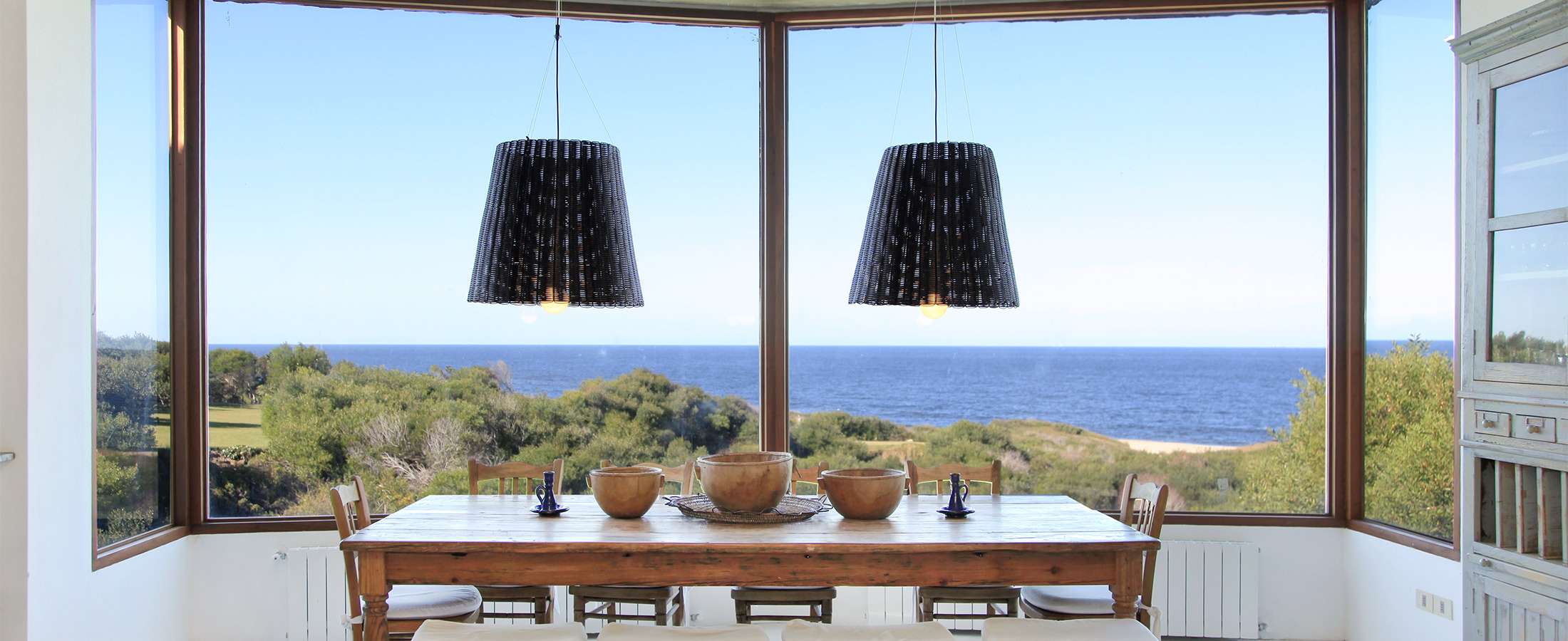 Dos lámparas en una casa frente la playa, y el mar en el horizonte